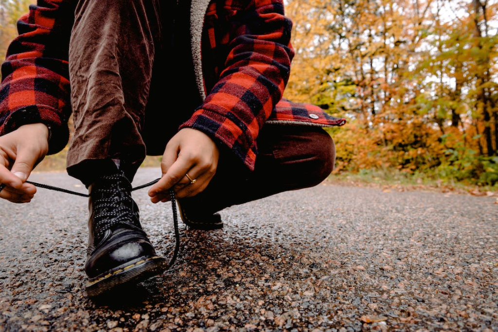 A person tying their shoelaces in the middle of a trail