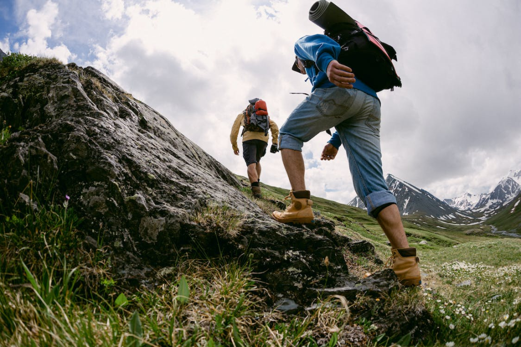 Two people with hiking gear and backpacks walking on a terrain