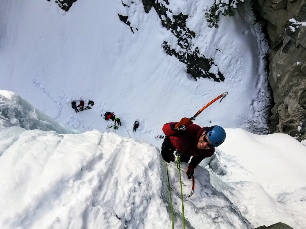 A group of people ice climbing up a snowy cliff.