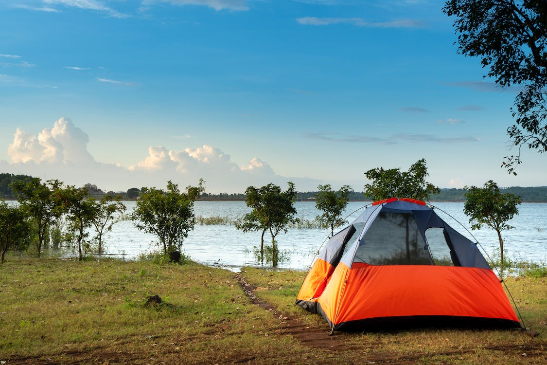 A tent on the ground next to a lake, perfect for camping and enjoying nature at its finest.