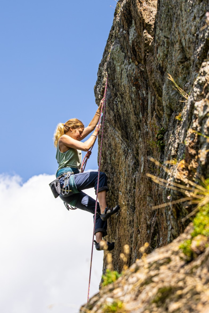 A woman climbing a mountain using ropes and pulleys