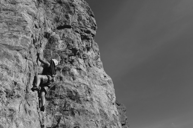 A black and white photo of an outdoor rock climber.