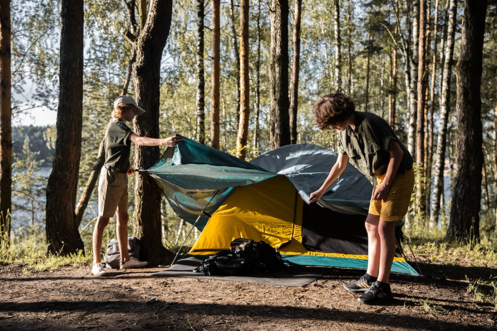 Two young boys setting up a camping tent