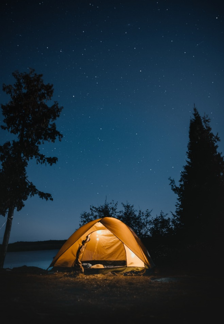 An adult camping tent is lit up at night with stars in the sky.