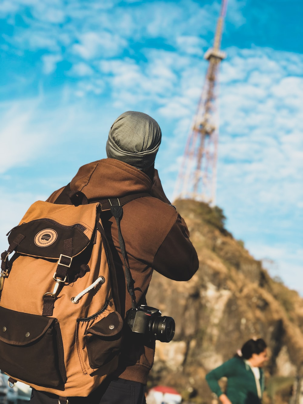 A man on his first backpacking trip stands in front of a tower, carrying his trusty backpack.