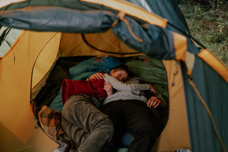 Two people enjoying one of the best camping spots in the woods, sleeping peacefully in a tent.