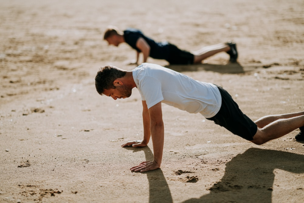 Two men training physically on a beach side.