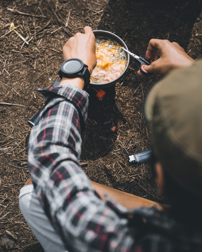 a camper adding ingredients to a soup while camping