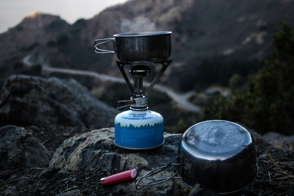 a portable camping stove next to a small pot