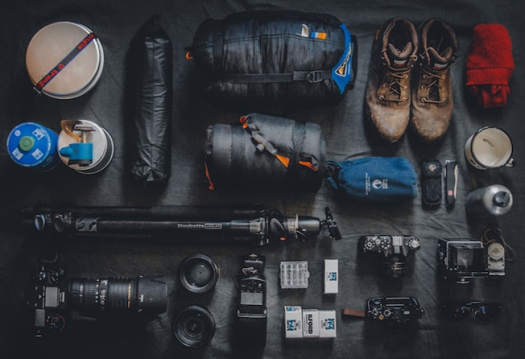 A photo of the best camping gear laid out on a table, including a camera and other items.