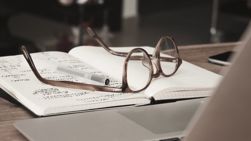 A pair of glasses placed on a research notebook.