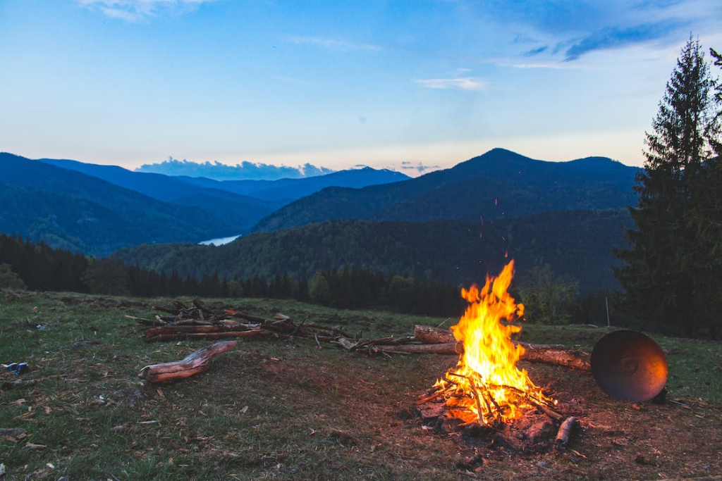 a campfire in an open field overlooking the mountains