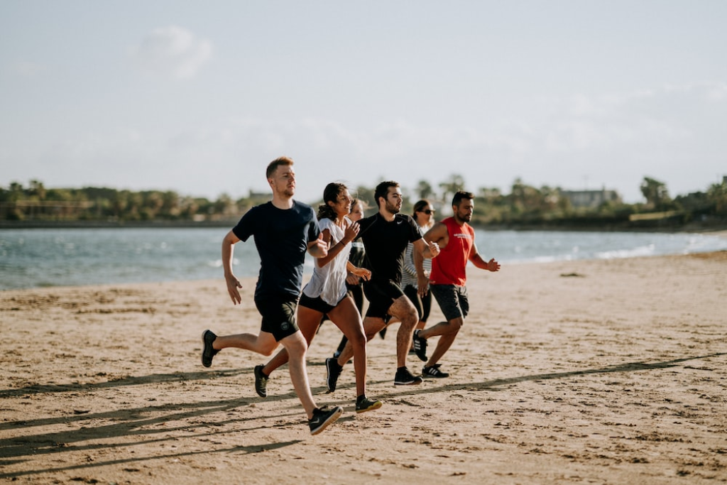 Several people running across a beach.