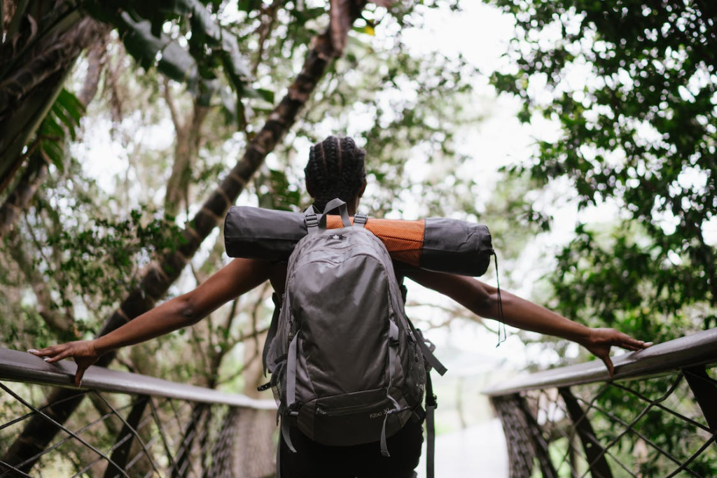 A hiker wearing a backpack and standing on a footbridge