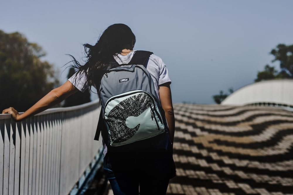 A woman walking on a bridge with a backpack.