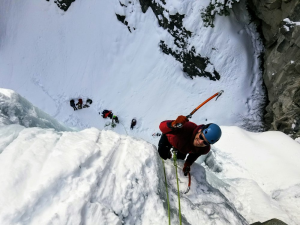 A group of people climbing up a snowy cliff.